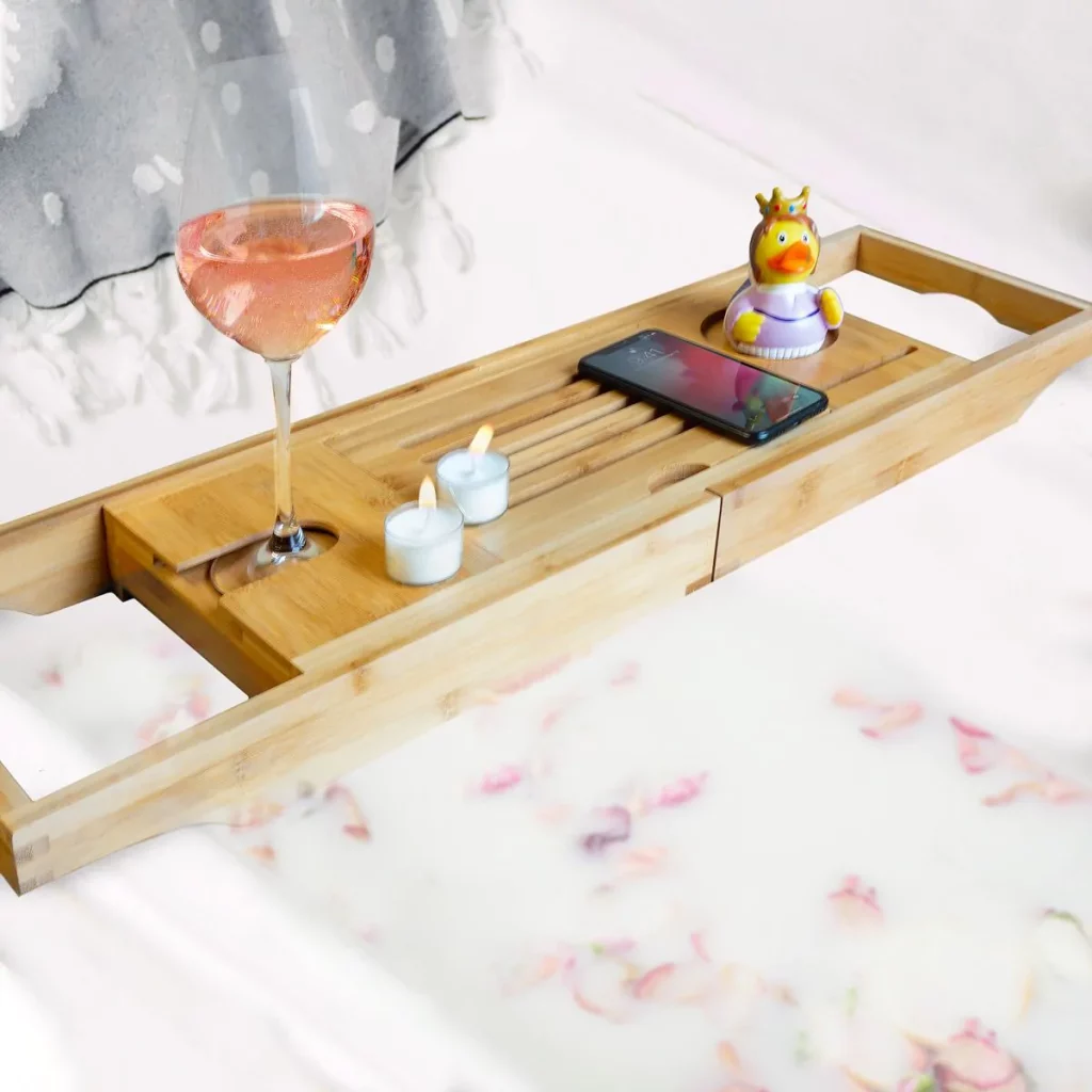 Ceci est une image d'un plateau en bambou avec un verre de vin, des bougies, ... au-dessus d'une baignoire.