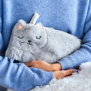 femme qui tient dans ses bras une bouillotte en forme de chat gris.