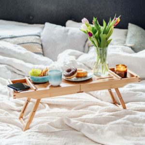 Plateau de baignoire en bambou avec des donuts et un bouquet de fleurs dessus