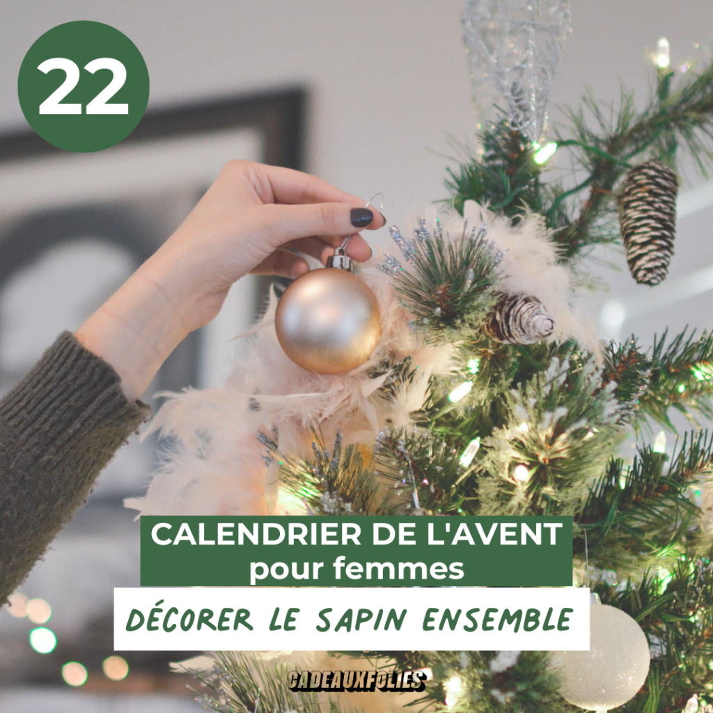 Main qui accroche une boule dans un sapin de Noel