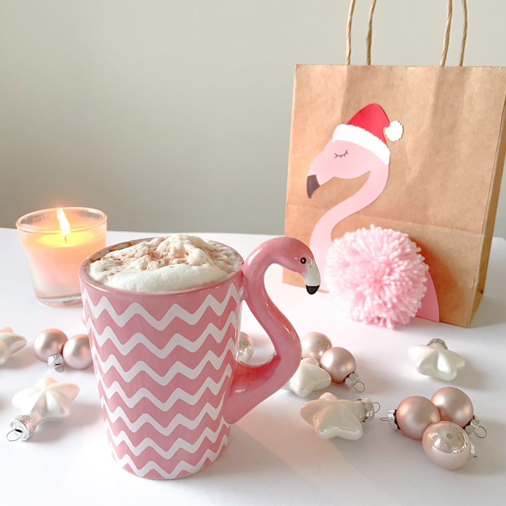 tasse flamant rose remplie de mousse blanche et pochette de noel flamant rose à côté