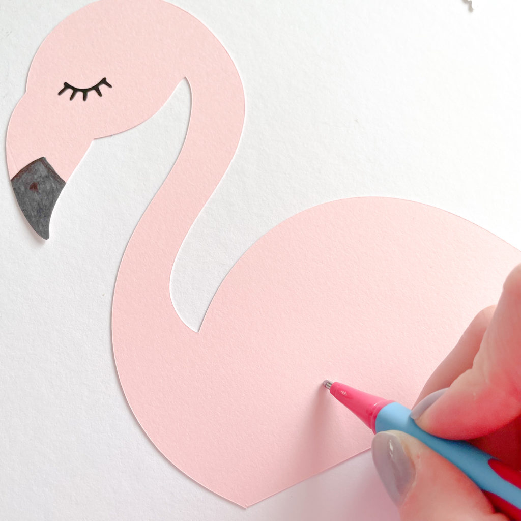stylo rose sur le point de dessiner une aile de sur la silhouette de flamant rose