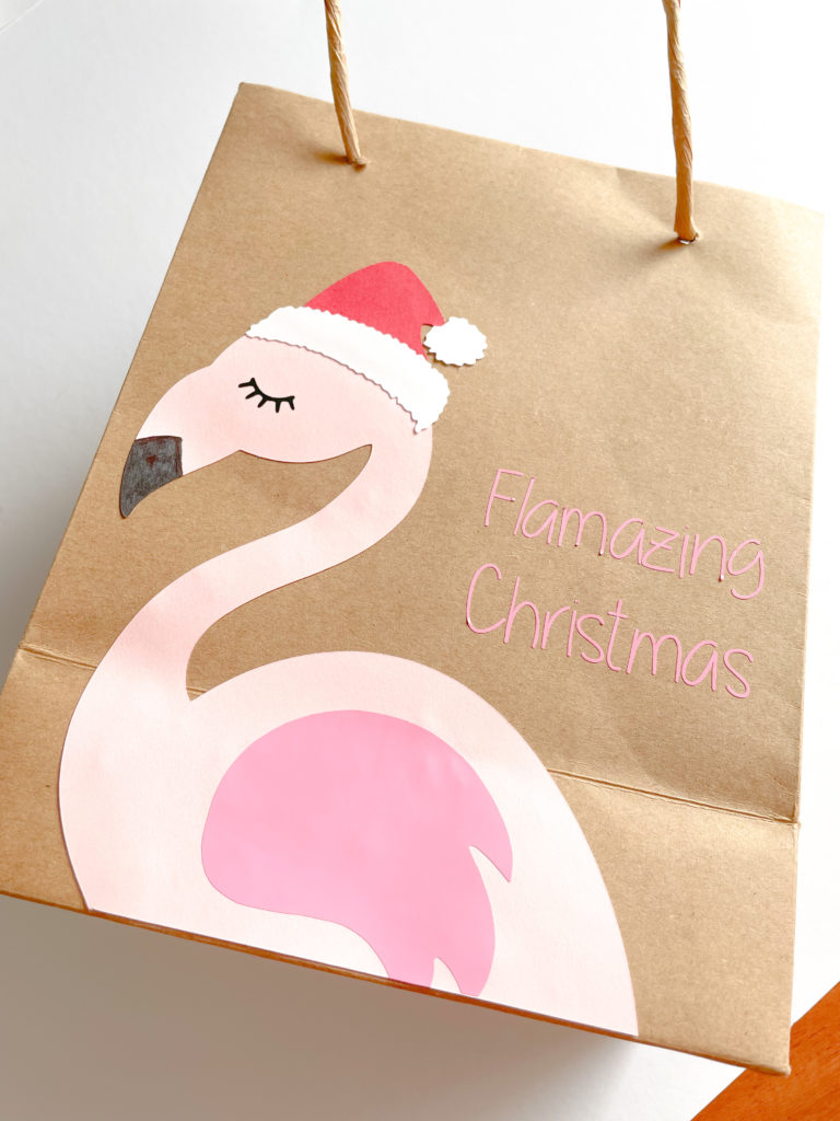 Pochette cadeau en papier avec un flamant rose dessus et l'inscription Flamazing Christmas