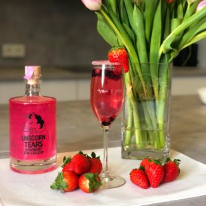 cocktail rouge avec des fraises et bouteille de gin licorne