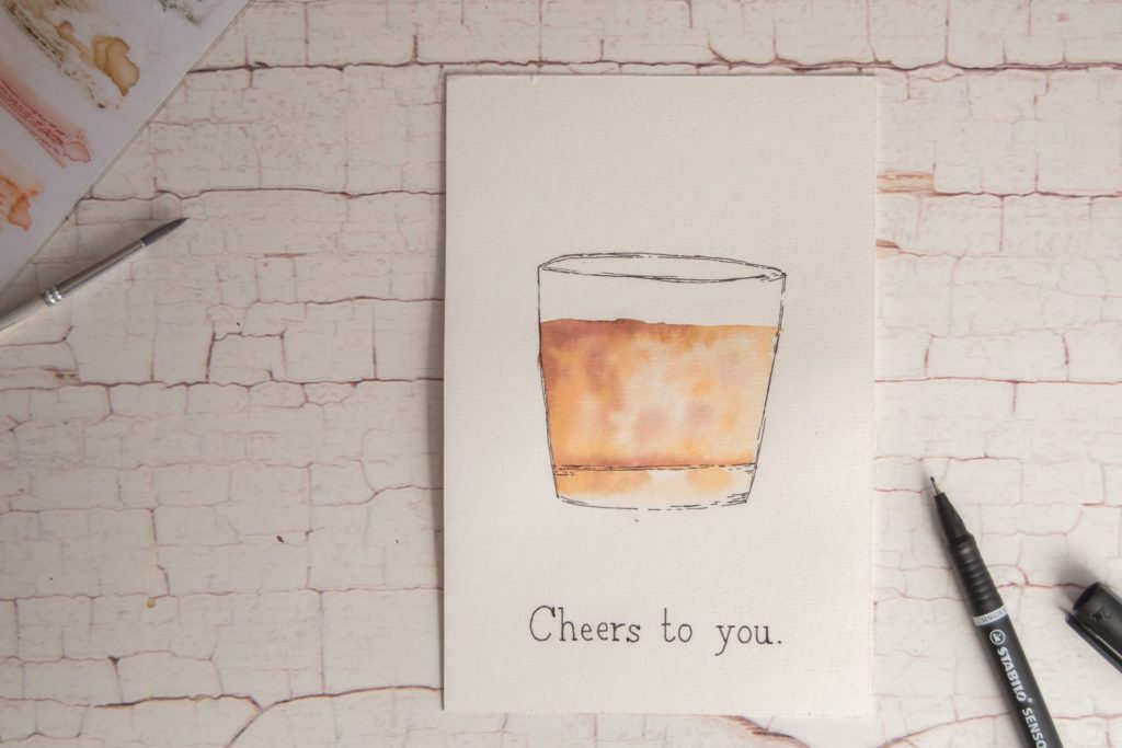Dessin aquarelle d'un verre rempli de whisky avec la mention "Cheers to you"