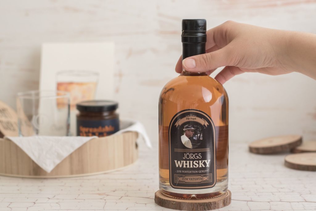 main touchant le haut d'une bouteille de whisky personnalisée