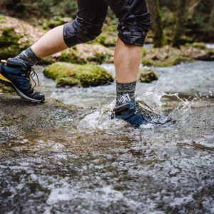 Jambes avec Chaussettes imperméables Impervius qui traversent une rivière