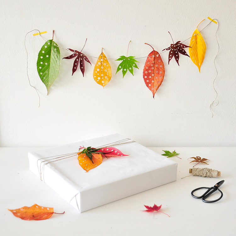 Décoration automne : Papier cadeau blanc avec une guirlande de feuilles colorées