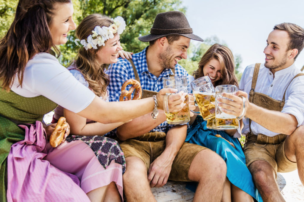 5 hommes et femmes en costumes traditionnels bavarois trinquent avec de la bière